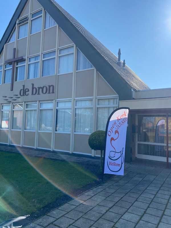 De Bron aan de Wollegrasstraat, met de vlag Open Kerk bij de ingang.